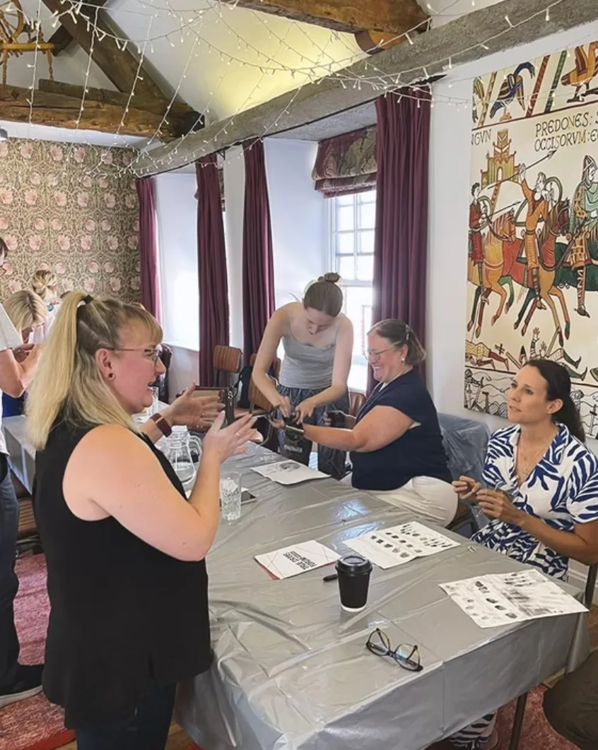 Attendees around a table with printed worksheets during a hands-on workshop at the 2025 True Crime Forum